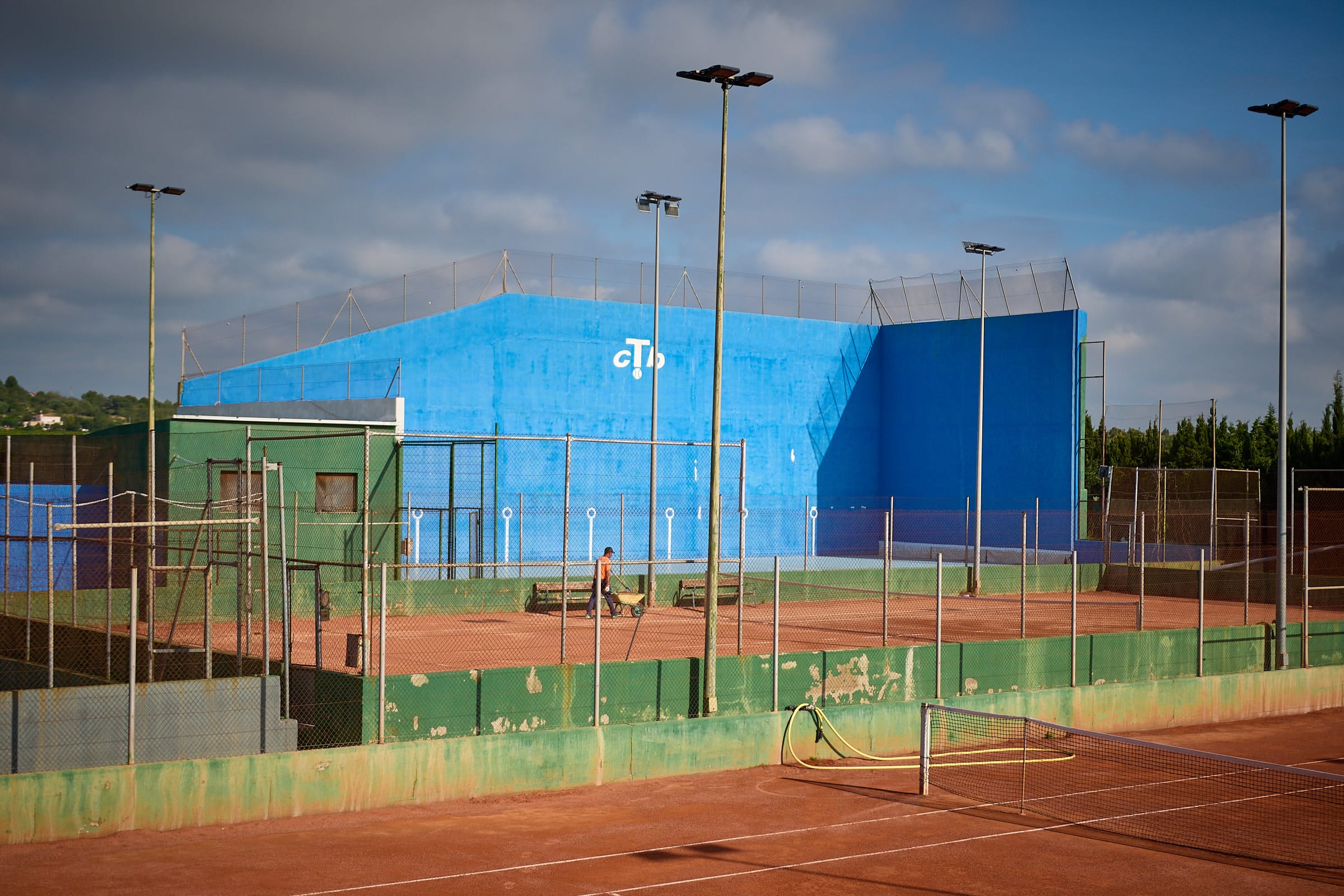 Fronton bleu du Club avec les courts de tennis au premier plan